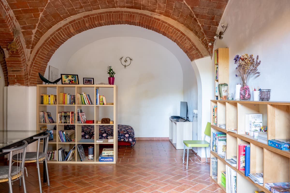 Soggiorno sotto la volta in mattone, con libreria e pavimento in cotto
