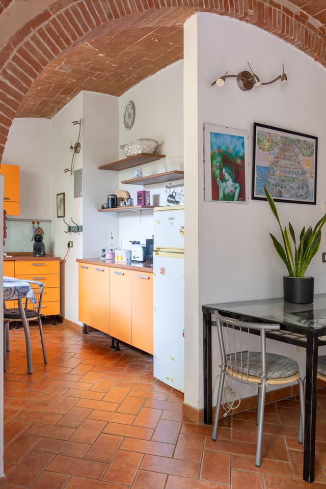 Angolo cucina con mobili arancioni, visto dall’arco