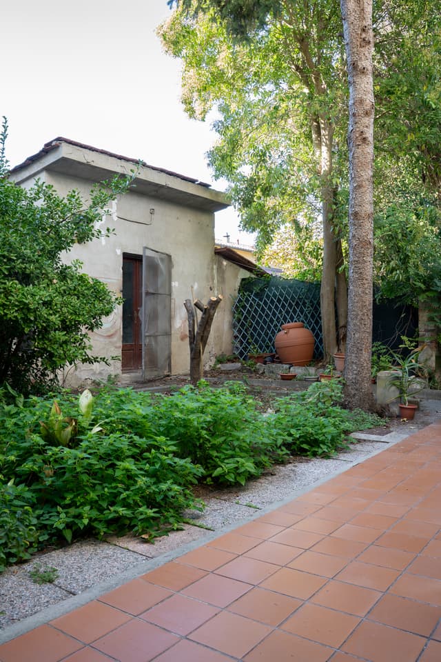 Giardino con vialetto in cotto e ripostiglio sul fondo